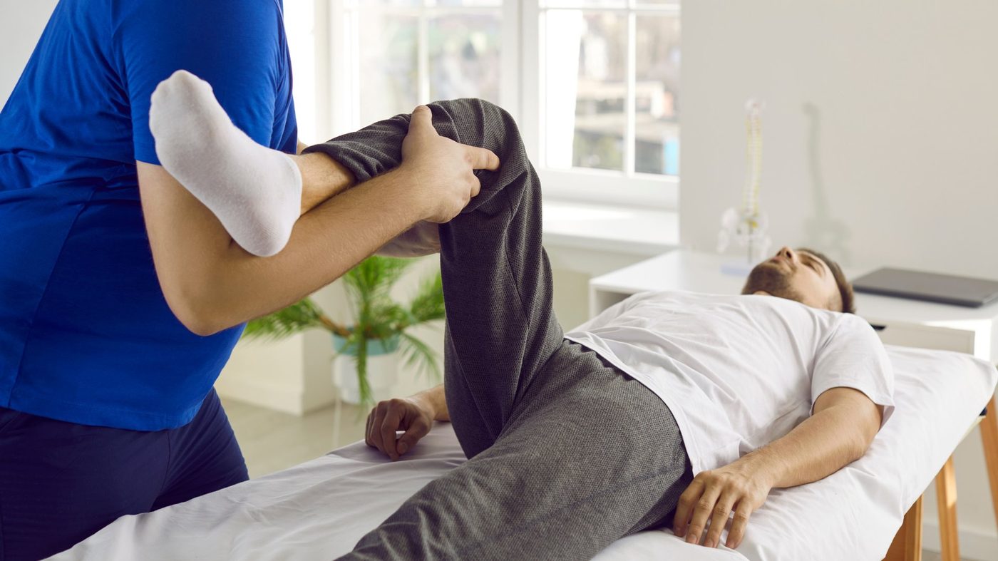 Osteopath performing leg mobilization on a patient during a hands-on sports injury treatment